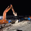 Xe máy xúc vận chuyển những tấm thép lớn để làm đường cho xe cần cẩu hạng nặng tiếp hiện trường tàu gặp nạn. (Ảnh: Nguyên Linh/TTXVN)