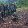 Các thành viên Đội tìm kiếm, quy tập hài cốt Liệt sĩ sử dụng máy dò mìn để đảm bảo khu vực tìm kiếm "sạch" trước khi tiến hành tìm kiếm. Ảnh: Hoàng Hiếu - TTXVN