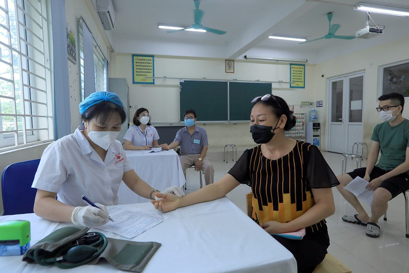 Nhân viên y tế phường Kim Giang khám sàng lọc cho người dân trước khi tiêm. (Ảnh: Phan Tuấn Anh/TTXVN)