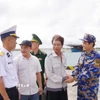 Ngư dân Tiêu Viết Bút (thứ 2 bên phải sang) bắt tay tạm biệt cán bộ, chiến sỹ trên đảo Trường Sa trước khi trở lại tàu cá. (Ảnh: TTXVN phát)