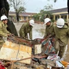 Lực lượng Quân đội hỗ trợ người dân thu dọn rác và bùn đất sau khi nước rút. (Ảnh: Nguyên Dung/TTXVN)