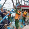 Lực lượng Đồn Biên phòng Quỳnh Phương (Bộ đội biên phòng tỉnh Nghệ An) hỗ trợ ngư dân chằng buộc trên tàu đánh cá trước cảnh báo bão, ngày 21/7/2025. (Ảnh: TTXVN phát)