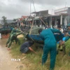Các lực lượng hỗ trợ giúp đỡ người dân chằng chống, bảo vệ phương tiện trước khi bão vào đất liền. (Ảnh: Đoàn Hữu Trung/TTXVN)