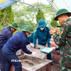 Các lực lượng tham gia khai quật, lấy mẫu AND phần mộ liệt sỹ. (Ảnh: Hữu Quyết/TTXVN)
