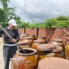 Chị Trương Thị Bốn (Chủ cơ sở Nước mắm Cửa Khe Bốn Thái) cho biết mắm phải ủ trên 12 tháng thì mới đậm vị, thơm ngon. (Ảnh: Quốc Dũng/TTXVN)