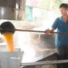 Một mẻ mật mía trải qua khoảng thời gian nấu từ 3 đến 4 giờ. Trong đó, hơn nửa thời gian mật mía mới sủi tăm và sôi. Khi mật mía sôi, người nấu phải luôn tay vớt bọt và tạp chất nổi lên trong các chảo nấu để đảm bảo mật mía có chất lượng, màu sắc đẹp. (Ảnh: Xuân Tiến/TTXVN)