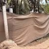 Vì quá bụi, người dân phải “khẩu trang” bằng lưới cho hàng rào nhà. (Ảnh: Cao Nguyên/TTXVN)