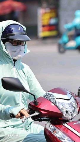 Mỗi khi phải ra đường, dù người lớn hay trẻ em đều dùng mọi biện pháp như khẩu trang hay áo chống nắng để chống lại cái nắng nóng gay gắt. (Ảnh: Minh Đức/TTXVN)