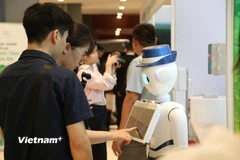 Khách tham quan trải nghiệm thiết bị ứng dụng công nghệ tại khu vực triển lãm. (Ảnh: Phương Nguyễn/Vietnam+)