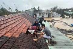 Lũ dâng cao, người dân phải phá mái nhà leo lên để tránh nguy hiểm ở Gia Lai. (Ảnh: TTXVN phát)