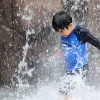 Em nhỏ làm mát dưới đài phun nước ở Incheon, Hàn Quốc ngày 13/7. (Ảnh: Yonhap/TTXVN)