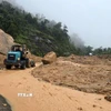 Lực lượng chức năng tỉnh Khánh Hòa huy động thiết bị cơ giới dọn dẹp đất đá bị sạt lở để tiếp cận hiện trường đưa nạn nhân ra ngoài. (Ảnh: Đặng Tuấn/TTXVN)