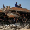 Người dân Palestine ngồi trên đống đổ nát ở khu vực Sudaniya, phía Bắc thành phố Gaza. (Ảnh: THX/TTXVN)
