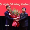 Ủy viên Bộ Chính trị, Giám đốc Học viện Chính trị quốc gia Hồ Chí Minh, Chủ tịch Hội đồng Lý luận Trung ương Nguyễn Xuân Thắng trao Quyết định và tặng hoa chúc mừng ông Đoàn Minh Huấn. (Ảnh: Văn Điệp/TTXVN)