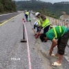 Lực lượng công nhân tiến hành nhồi sợi dây đay vào khe nứt rồi đổ nhựa đường nhằm ngăn nước thấm xuống phía dưới tại sự cố nứt đường trên Quốc lộ 1A, đoạn qua Đèo Ngang. (Ảnh: TTXVN phát)
