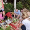 Khách nước ngoài trải nghiệm gói bánh Tét. (Ảnh: Mỹ Phương/TTXVN)