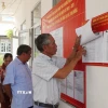 Người dân xem danh sách cử tri được niêm yết tại điểm bỏ phiếu. (Ảnh: Nhựt An/TTXVN)