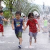 Các em nhỏ chơi đùa bên đài phun nước để tránh nóng tại Seoul, Hàn Quốc. (Ảnh: THX/TTXVN)