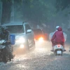 Mưa xối xả khiến phố Hàng Bài ngập nặng, ô tô phải bật đèn khi di chuyển. (Ảnh: Hoàng Hiếu/TTXVN)