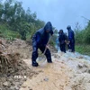 Các lực lượng đào, vét đất đá, mở rãnh thoát nước và thu dọn bùn đất tràn xuống mặt đường, tạo lối đi tạm để phương tiện qua lại. (Ảnh: TTXVN phát)