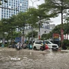 Người dân di chuyển qua tuyến phố Trung Kính bị ngập lụt sau mưa lớn. (Ảnh: Huy Hùng/TTXVN)