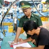 Cán bộ Đồn Biên phòng hướng dẫn ngư dân ký cam kết không vi phạm IUU. (Ảnh: Hồng Hiếu/TTXVN)