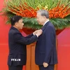 Đồng chí Trần Cẩm Tú, Ủy viên Bộ Chính trị, Thường trực Ban Bí thư trao Huy hiệu Đảng và tặng hoa chúc mừng Tổng Bí thư Tô Lâm. (Ảnh: Thống Nhất/TTXVN)