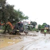 Máy cẩu, máy xúc được huy động tham gia vào việc san ủi bùn đất, sinh lầy tại một điểm ngập trên tuyến quốc lộ 7 qua địa bàn xã Con Cuông, tỉnh Nghệ An. (Ảnh: Xuân Tiến/TTXVN)