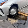 Ôtô mắc kẹt do rơi xuống hố sau khi mặt đường sụp lún. (Nguồn: Kyodo)