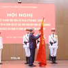 Tổng Bí thư Tô Lâm gắn huy hiệu “Anh hùng lực lượng vũ trang nhân dân” lên lá cờ truyền thống của Cục An ninh mạng và phòng, chống tội phạm sử dụng công nghệ cao, Bộ Công an. (Ảnh: Phạm Kiên/TTXVN)
