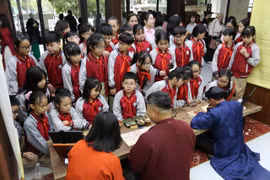 Các em học sinh trải nghiệm hoạt động tương tác tại không gian di sản “Thưởng lãm Châu phê - Lưu dấu Mộc bản.” (Ảnh: Việt Dũng/Vietnam+)