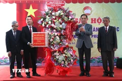 Bộ trưởng Bộ Ngoại giao Lê Hoài Trung trao quà và hoa chúc mừng cho Tổ dân phố Dạ Lê. (Ảnh: Mai Trang/TTXVN)