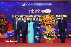 Đại diện Bộ Nội vụ tặng hoa chúc mừng tập thể nhà trường. (Ảnh: Hoàng Long/Vietnam+)