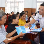 Cảnh sát biển phát tờ rơi tuyên truyền chống khai thác bất hợp pháp cho bà con ngư dân. (Ảnh: Đinh Hương/TTXVN)