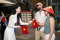 Du khách quốc tế được tặng cờ Tổ quốc tại Đường sách Thành phố Hồ Chí Minh. (Ảnh: CTV/Vietnam+)
