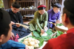 Thành viên CLB Đình làng Việt trong trang phục áo dài truyền thống cùng gói bánh chưng Tết. (Ảnh: Thanh Tùng/TTXVN)