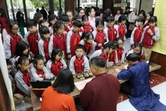 Các em học sinh trải nghiệm hoạt động tương tác tại không gian di sản “Thưởng lãm Châu phê - Lưu dấu Mộc bản.” (Ảnh: Việt Dũng/Vietnam+)