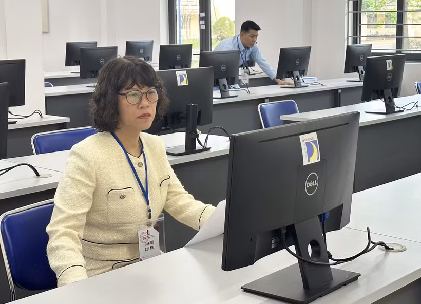 Cán bộ coi thi đánh giá tư duy kiểm tra máy tính trước giờ thi. (Ảnh: PV/Vietnam+)