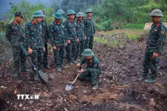 Các thành viên Đội tìm kiếm, quy tập hài cốt Liệt sĩ sử dụng máy dò mìn để đảm bảo khu vực tìm kiếm "sạch" trước khi tiến hành tìm kiếm. Ảnh: Hoàng Hiếu - TTXVN