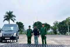 Đối tượng Hoàng Văn Bình (đứng giữa) (sinh năm 1991, trú tại xã Đông Ngũ, tỉnh Quảng Ninh) cùng tang vật và phương tiện bị lực lượng Biên phòng bắt giữ. (Ảnh: TTXVN phát)