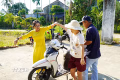 Thầy cô, người thân dìu các em khuyết tật vào dự lễ khai giảng. (Ảnh: Lê Phước Ngọc/TTXVN)
