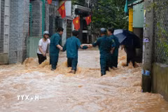 Lực lượng dân quân phường Phước Tân, thành phố Đồng Nai cố băng qua dòng nước chảy xiết để hỗ trợ người dân. (Ảnh minh họa: Lê Xuân/TTXVN)