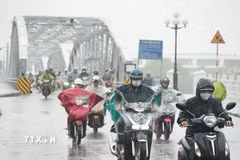 Người dân đi lại trong mưa lớn ở phía Nam cầu Trường Tiền, trung tâm thành phố Huế. (Ảnh: Nguyên Lý/TTXVN)