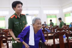 Lực lượng Công an hỗ trợ thân nhân các liệt sỹ đến lấy mẫu ADN tại Vĩnh Long. (Ảnh: Lê Thúy Hằng/TTXVN)