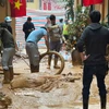 Người dân và công nhân được huy động nhằm khắc phục sự cố tràn bùn. (Ảnh: Minh Hiếu/Vietnam+)