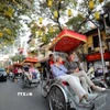 Du khách nước ngoài sử dụng xích lô thưởng ngoạn nét đẹp cổ kính của Phố cổ Hà Nội. (Ảnh: Thanh Tùng/TTXVN)