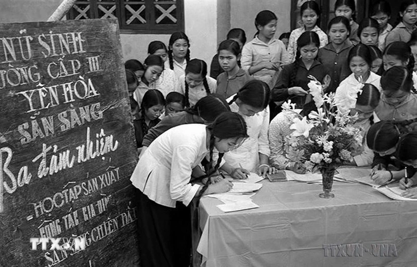 Phong trào phụ nữ “Ba đảm đang” năm 1965 nhanh chóng phát triển thành cao trào cách mạng sôi nổi, rộng lớn, huy động được sức mạnh tổng hợp của hàng chục triệu phụ nữ từ nông thôn tới thành thị, từ miền ngược đến miền xuôi, trên mọi lĩnh vực hoạt động. Trong ảnh: Học sinh trường cấp III Yên Hòa, Hà Nội đăng ký phong trào “Ba đảm nhiệm,' sau này là phong trào phụ nữ “Ba đảm đang”. (Ảnh: Thanh Tụng/TTXVN)