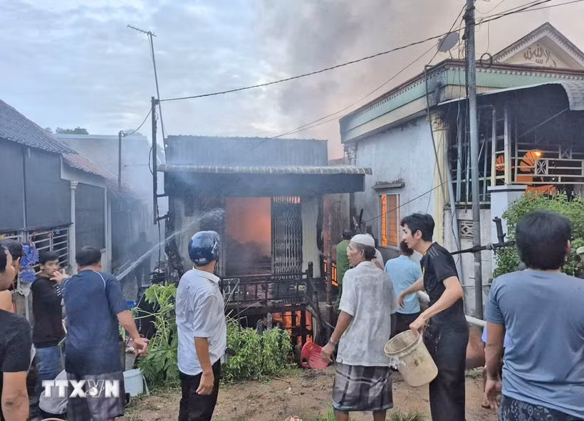 Người dân phối hợp với các lực lượng chức năng nỗ lực khống chế đám cháy, không để lan rộng sang những ngôi nhà liền kề. (Ảnh: TTXVN phát)