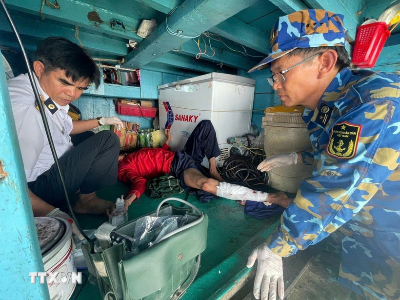 Tổ Quân y xử lý, băng nẹp cố định chân gãy cho ngư dân. (Ảnh: TTXVN phát)