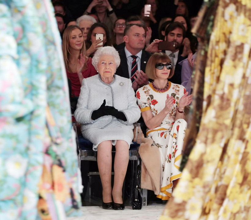 Nữ hoàng Elizabeth II quá cố ngồi cạnh Dame Anna Wintour tại buổi trình diễn thời trang của Richard Quinn trong Tuần lễ thời trang London năm 2018. (Ảnh: PA)
